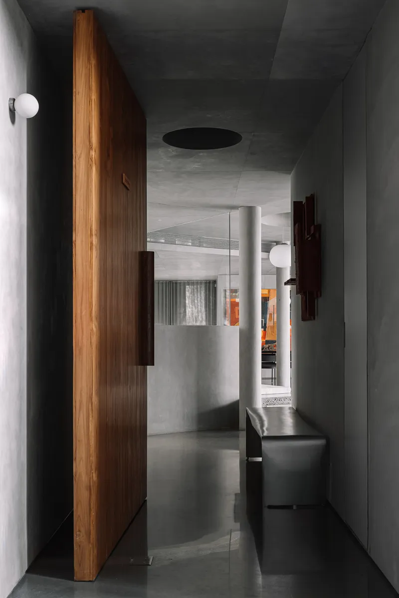 Corridor with vertical timber wall panel and circular ceiling void opening to upper level