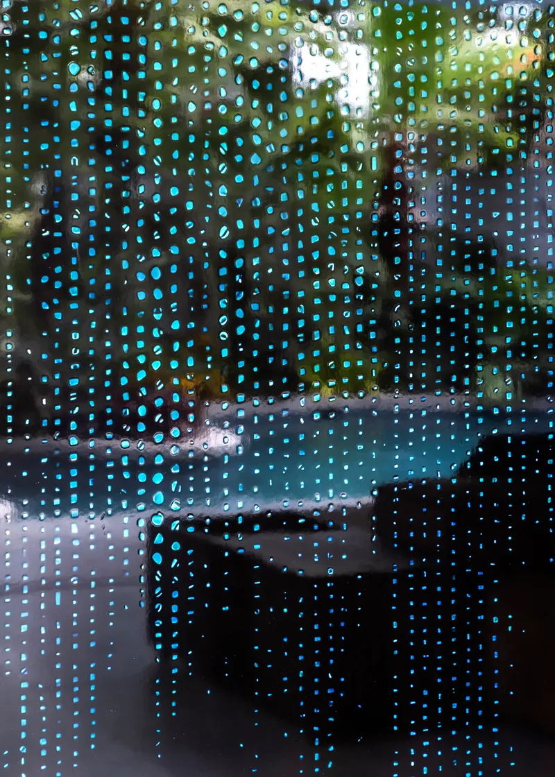 Close-up of perforated metal screen with blurred garden foliage visible through the pattern