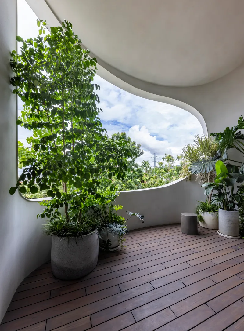 Curved balcony with timber decking and concrete planters under a partly cloudy sky