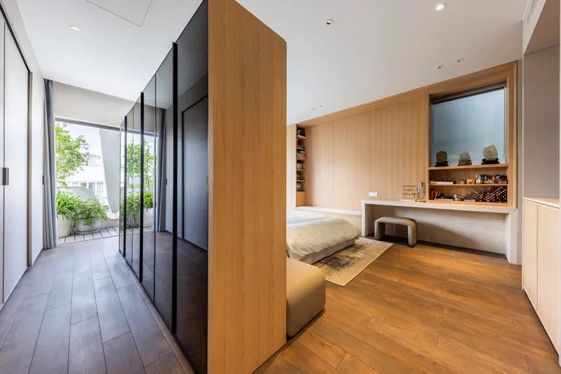 Bedroom with timber-clad partition and dark wardrobes opening to a planted terrace