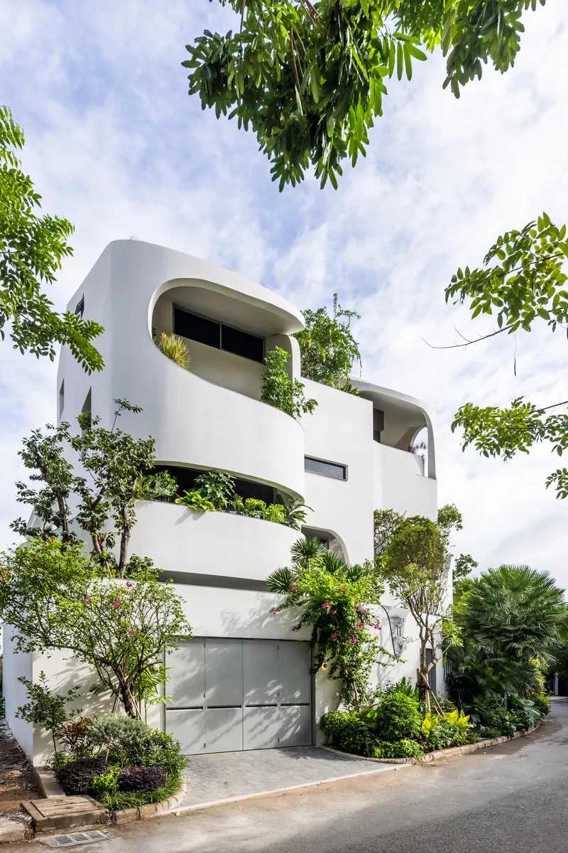 Street view of the white stacked volumes with integrated planters and climbing greenery