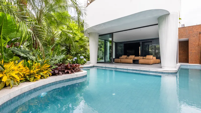 Swimming pool with planted island bed wrapping around a covered terrace with fluted columns