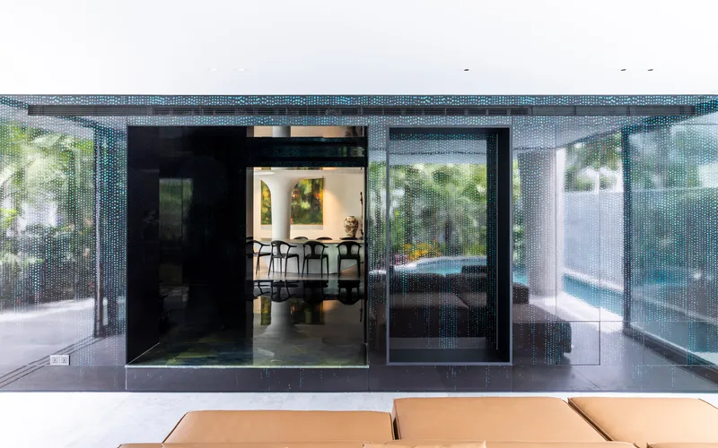 Covered terrace with perforated metal screens framing views to the dining area and pool beyond