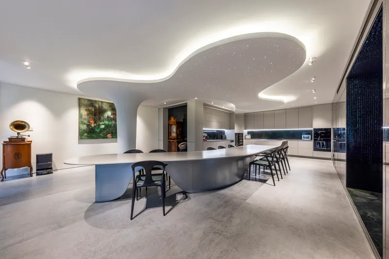 Open-plan kitchen with curved island, organic ceiling feature, and concealed uplighting