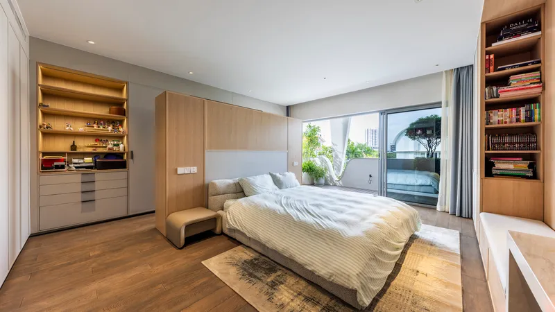 Bedroom with light wood millwork and built-in shelving framing a sliding glass door to a balcony
