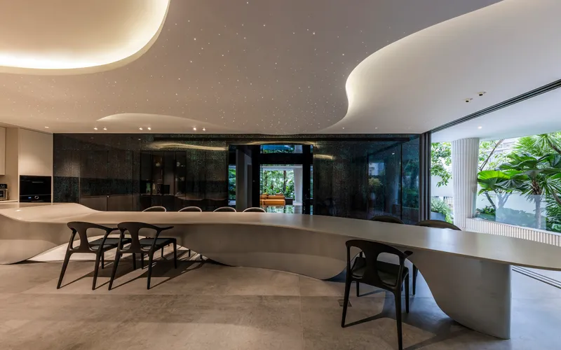 Dining area with curved white counter and backlit ceiling clouds beneath black cabinetry