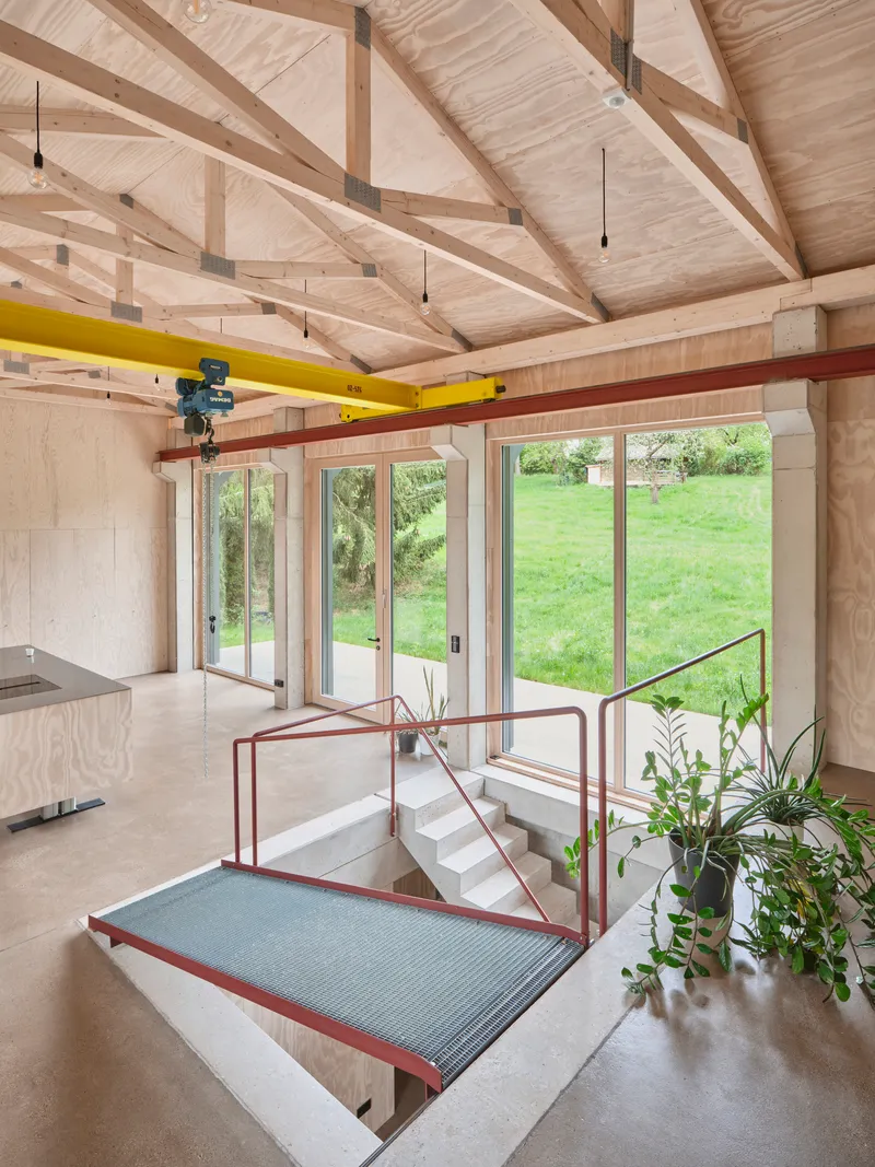 Sunken level connected by stairs with red metal railing and potted plants overlooking the sloped lawn