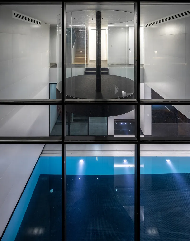Sectional view through glass floors revealing stacked levels with swimming pool and central black column