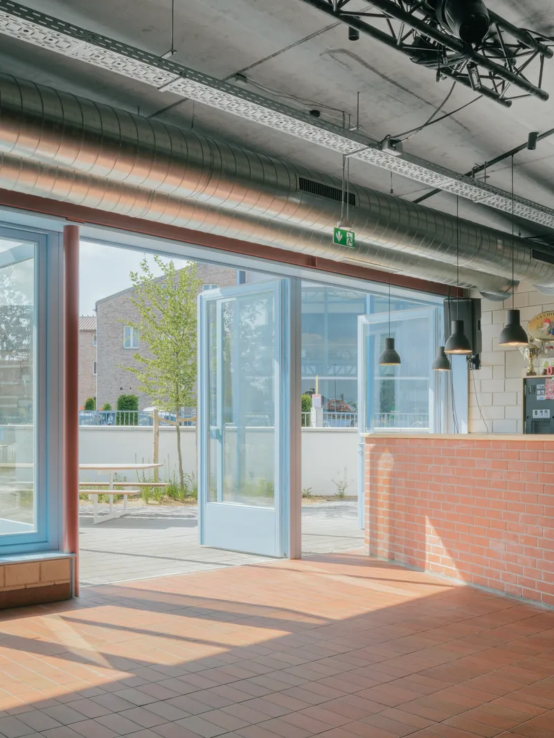 Interior view showing exposed concrete ceiling with steel trusses and glazed doors opening to the courtyard