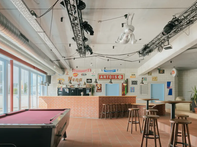 Interior bar area with terracotta floor tiles, exposed ductwork, pendant lights and a pink pool table in the foreground