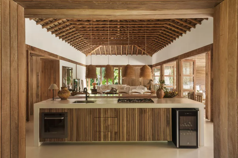 Open kitchen island beneath exposed timber roof trusses with view through to living area
