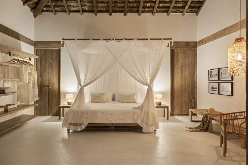 Bedroom with canopy bed and exposed timber roof structure beneath woven ceiling panels