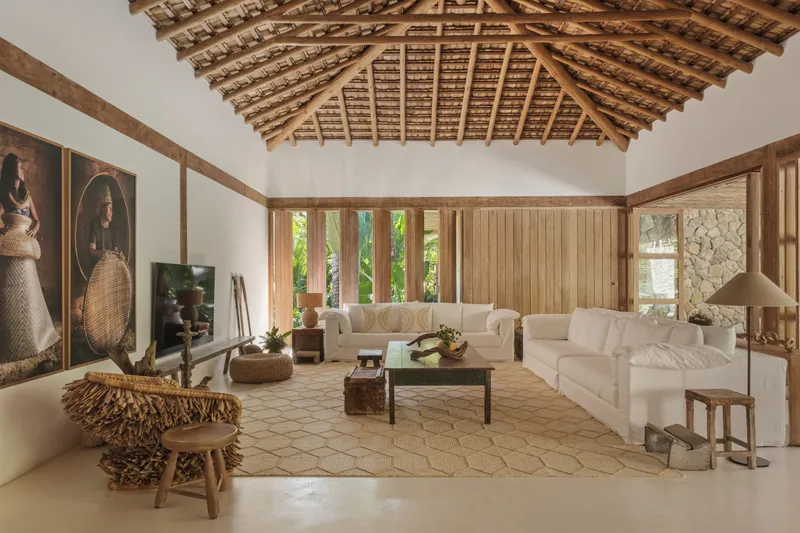 Living room with exposed timber roof structure and vertical timber slat window wall framing garden views