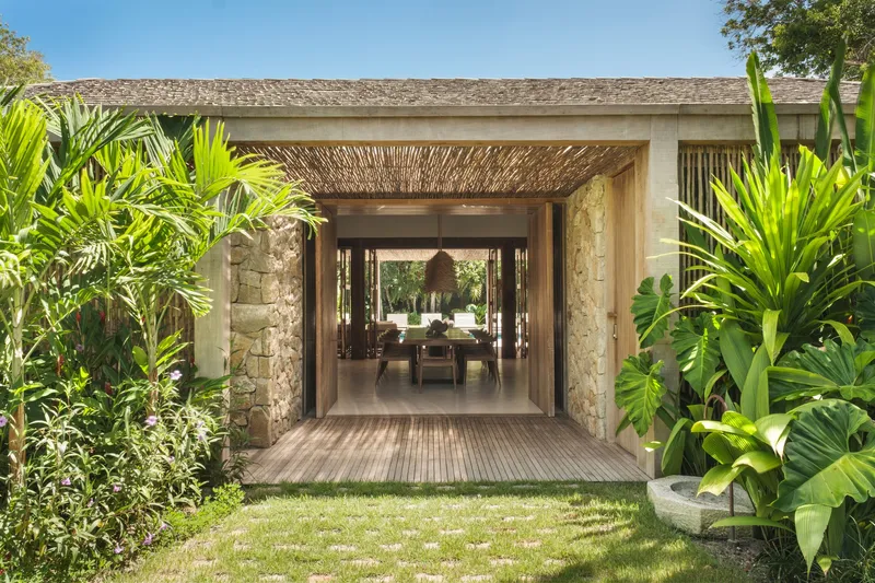 Garden approach through lush tropical planting to covered entry passage with woven timber ceiling screen