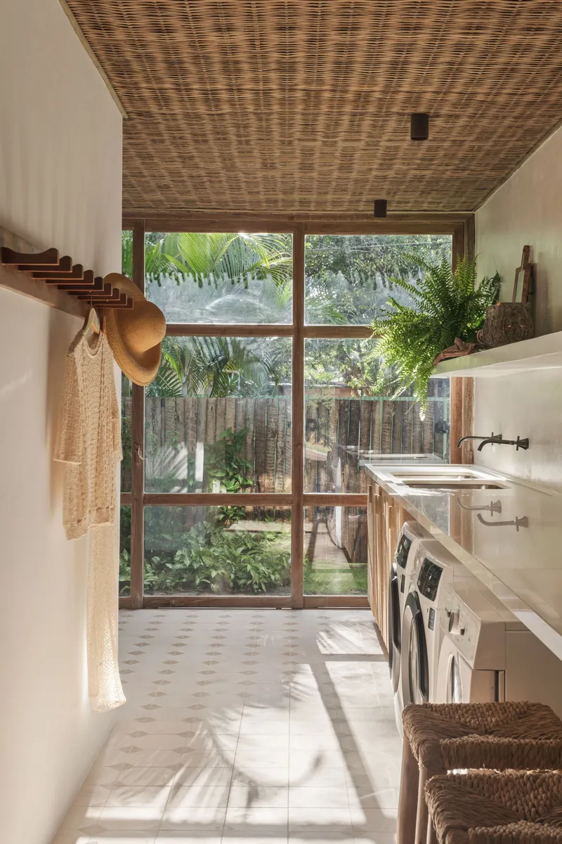 Laundry room with woven ceiling panels and full-height glazed wall overlooking interior courtyard garden