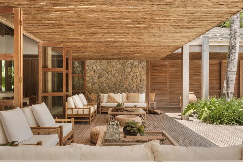 Covered timber deck terrace with stone wall backdrop and louvered privacy screens under slatted pergola
