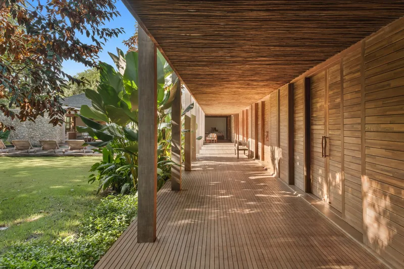 Covered timber walkway with vertical wood cladding and exposed rafters, looking toward pool and garden