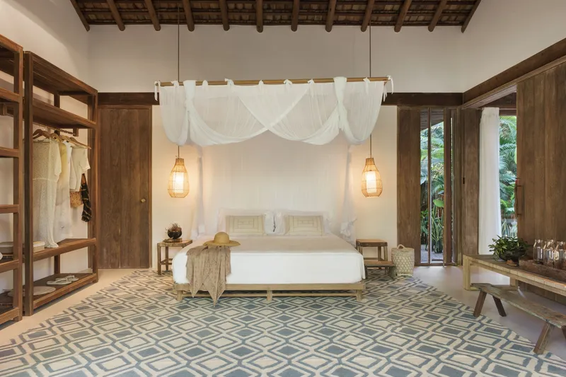 Bedroom with exposed timber ceiling, white canopy bed and patterned floor tiles beneath pendant lights