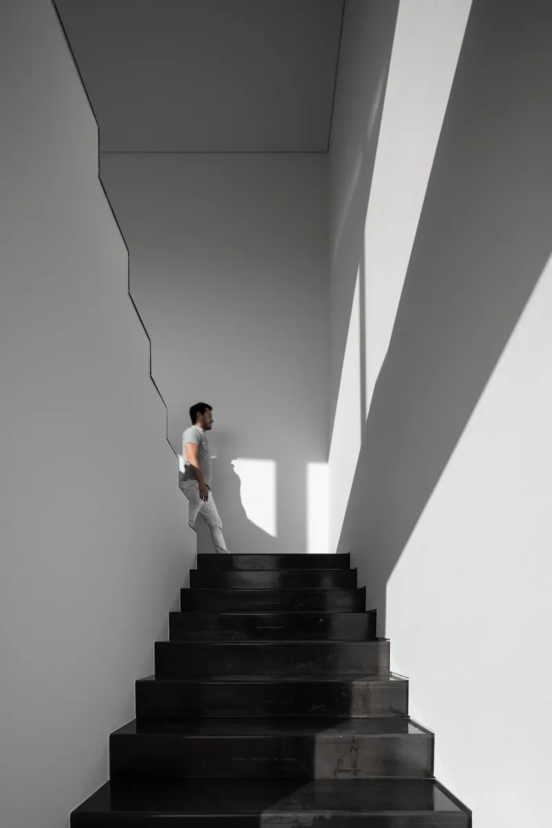 Sculptural stairwell carved in light and shadow, defining a minimalist spatial experience.