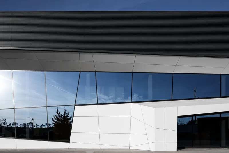 Angular façade with dynamic glazing reflecting sky and surroundings.