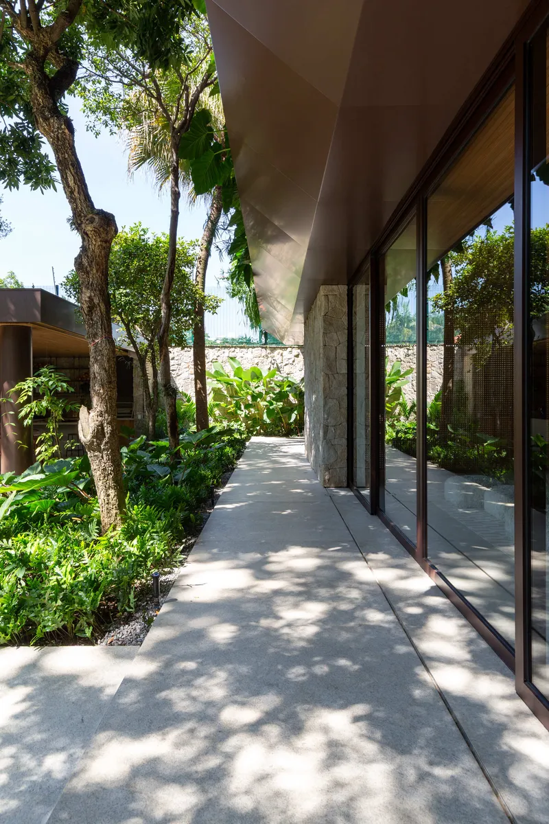 Covered walkway with sliding glass doors flanked by preserved trees and filtered shadow patterns