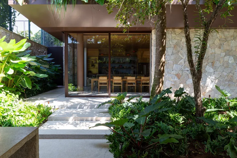 View into dining area through open glass doors with stone wall and mature tree trunks