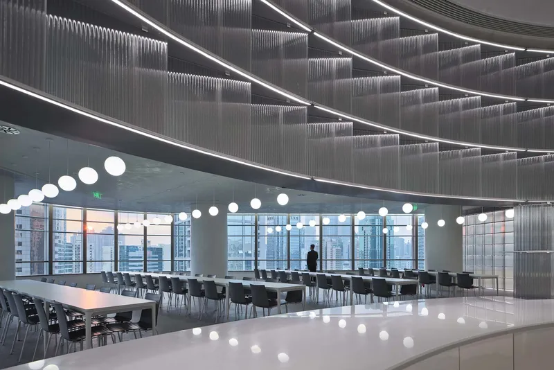Cafeteria space with ribbed metal ceiling panels, linear lighting, and pendant globes reflected on polished floor
