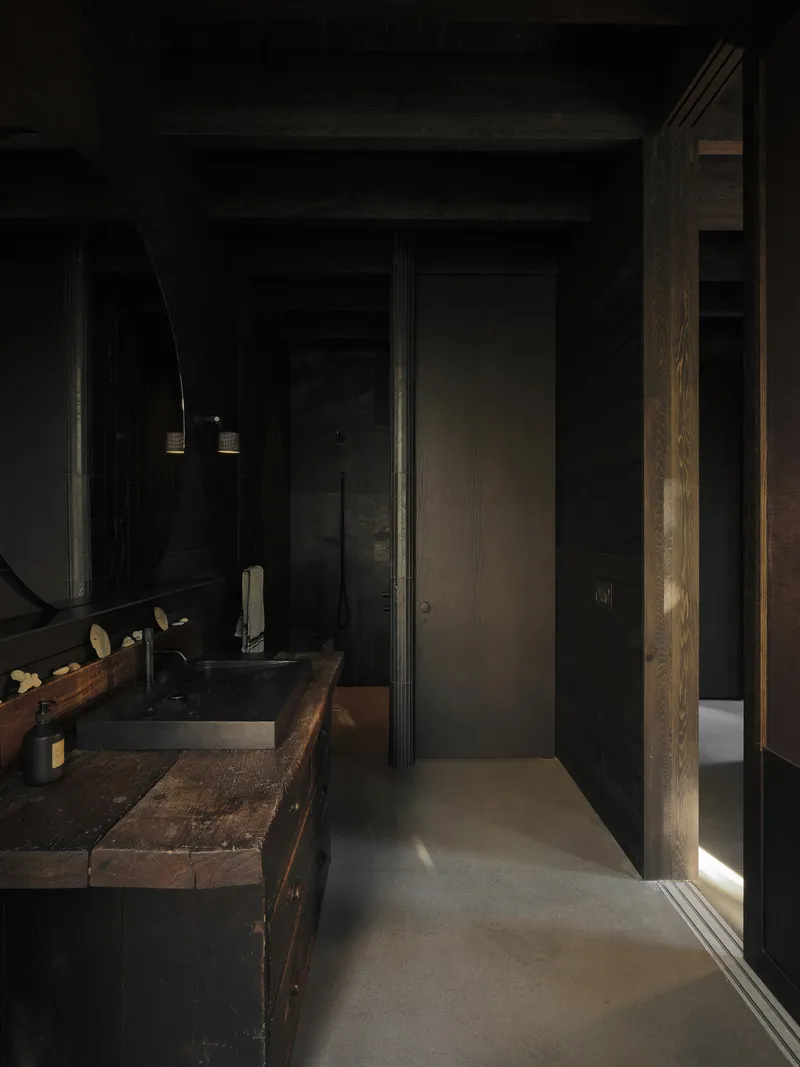 Narrow bathroom corridor with reclaimed wood vanity and vertical strip of natural light at edge