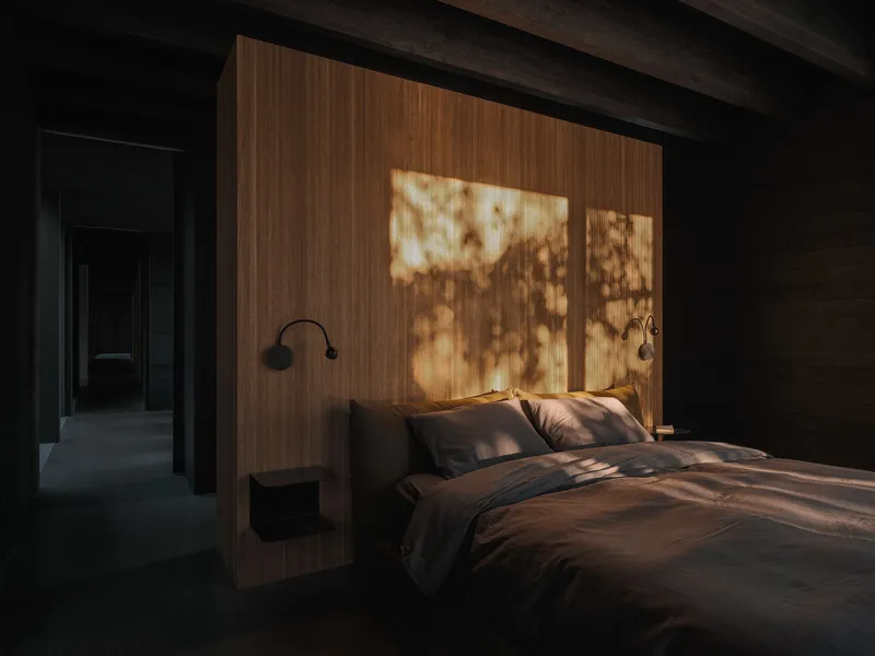 Bedroom with walnut headboard wall casting tree shadow patterns in warm afternoon sun