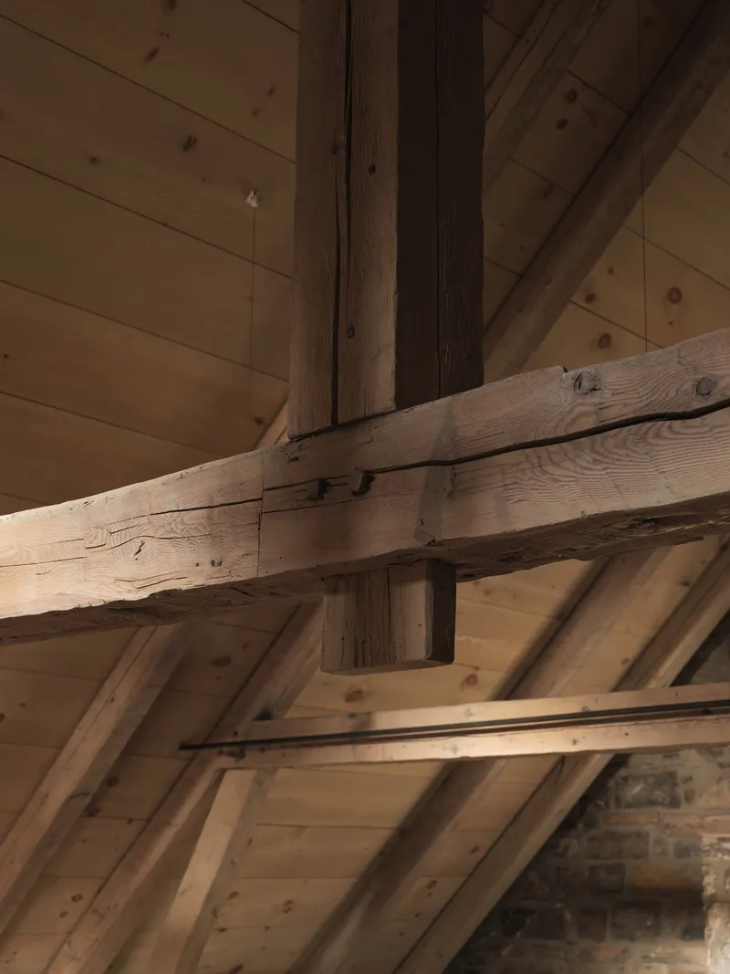Exposed timber roof trusses and joinery connecting beams against tongue-and-groove ceiling boards