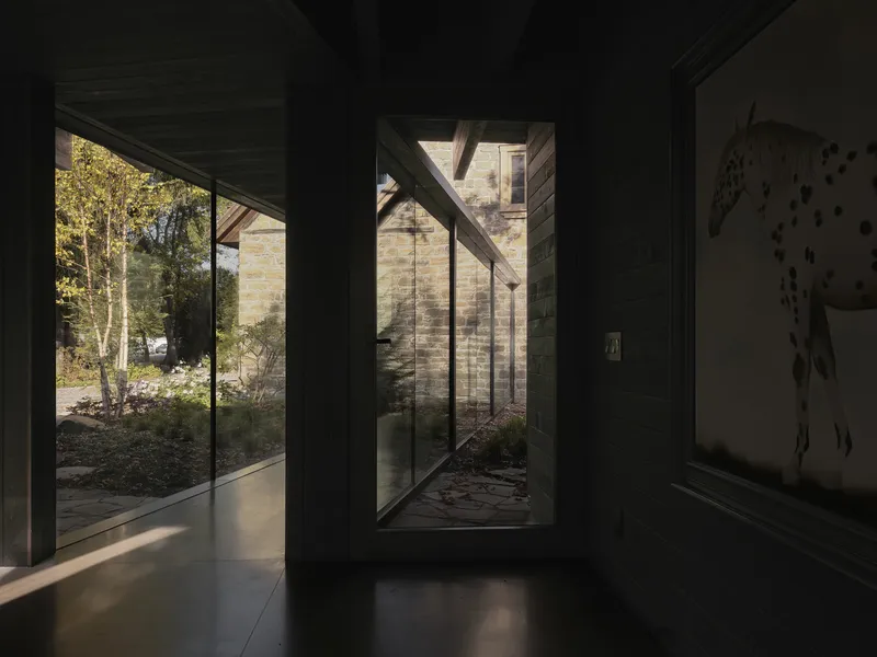 Interior hallway with tall glazed openings framing planted courtyards in afternoon light