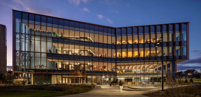 Fully glazed facade revealing illuminated interior floors and staircase at dusk
