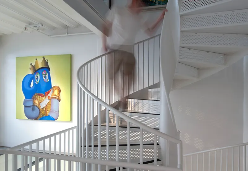 White spiral staircase with perforated metal treads and vertical bar railings with a figure in motion