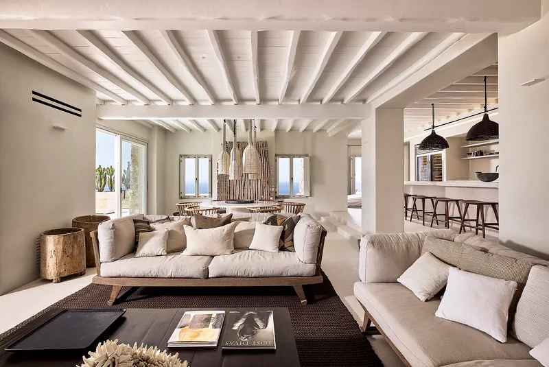 Open plan living space with white painted timber beams and ocean views through multiple openings