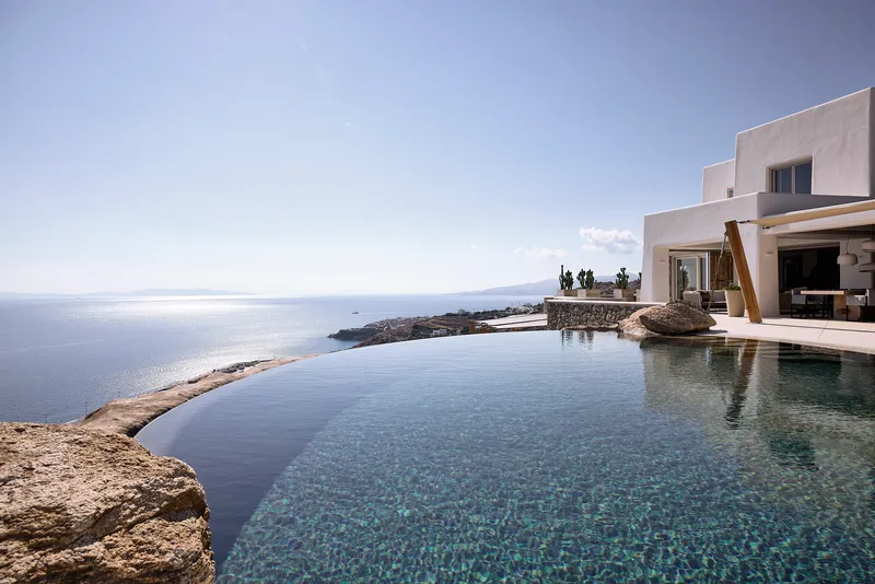 Infinity pool merging with the sea horizon framed by natural rock formations under clear sky