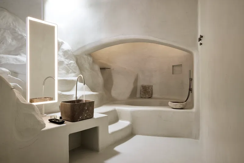 Vaulted bathroom grotto with plastered walls and stone sink alcove casting soft shadows