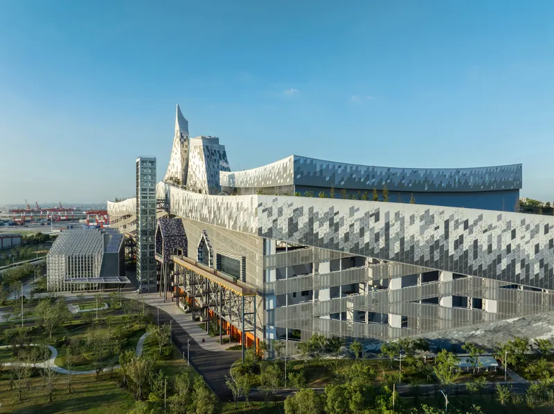 Aerial view of the patterned metal panel facades and angular volumes rising above the landscaped park