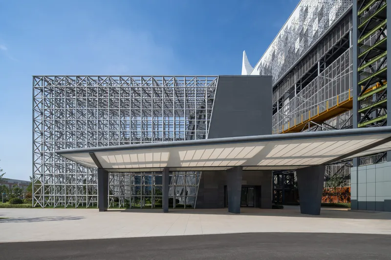 Entry plaza showing the cantilevered canopy and exposed steel truss facade under clear blue sky