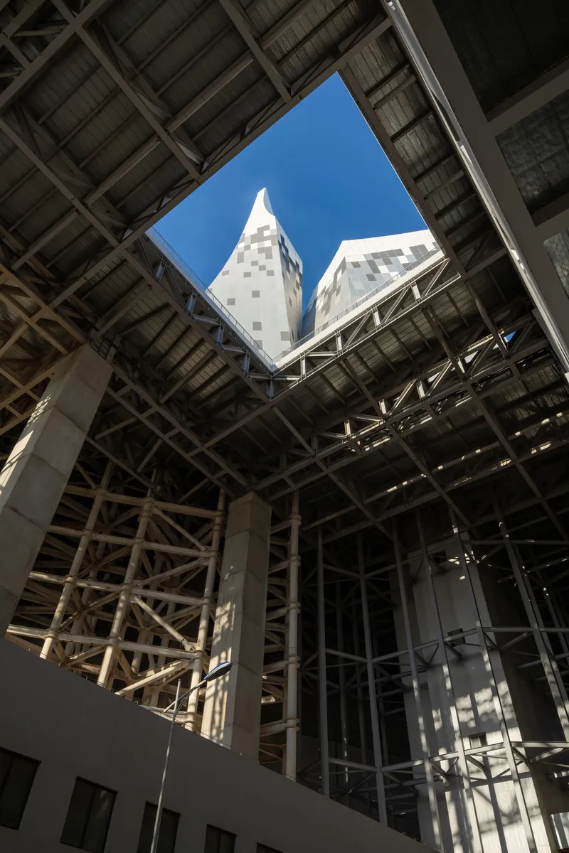 Looking up through the interior atrium framed by exposed steel trusses to the pyramidal towers above