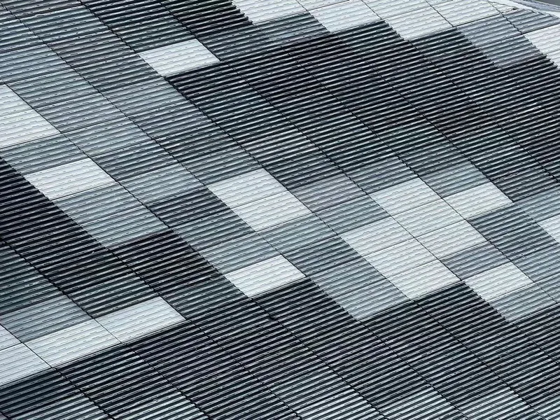 Detail of the horizontal metal louvered facade with scattered white panel openings in a pixelated pattern