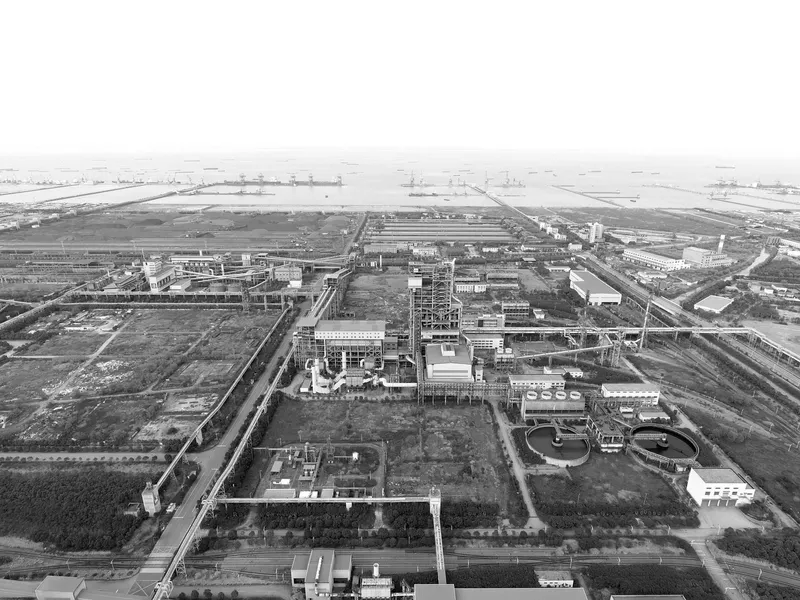 Aerial view of an industrial complex with rectangular buildings and infrastructure under hazy skies