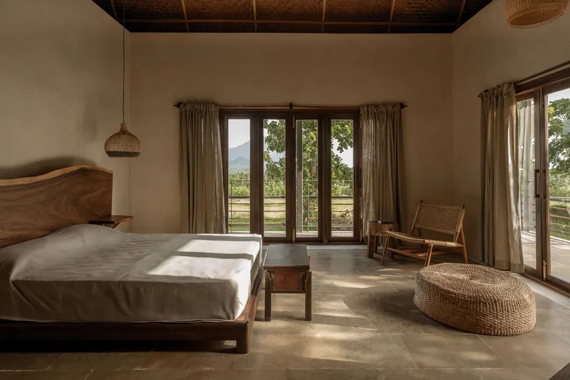 Bedroom with woven bamboo ceiling and timber-framed glazed doors opening to a mountain view