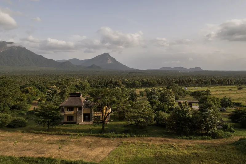 Elevated view of the residence among trees with mountain range in the distance at dusk