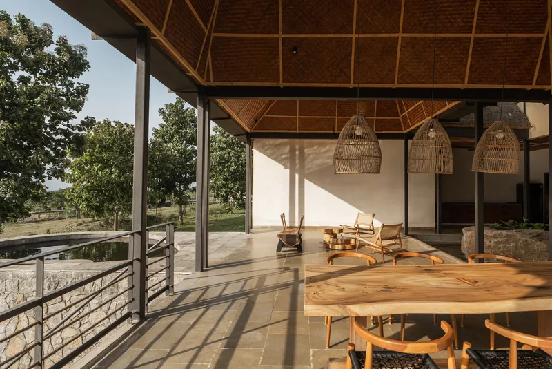 Covered terrace with diagonal lattice timber ceiling, woven pendant lights and patterned shadows on stone floor