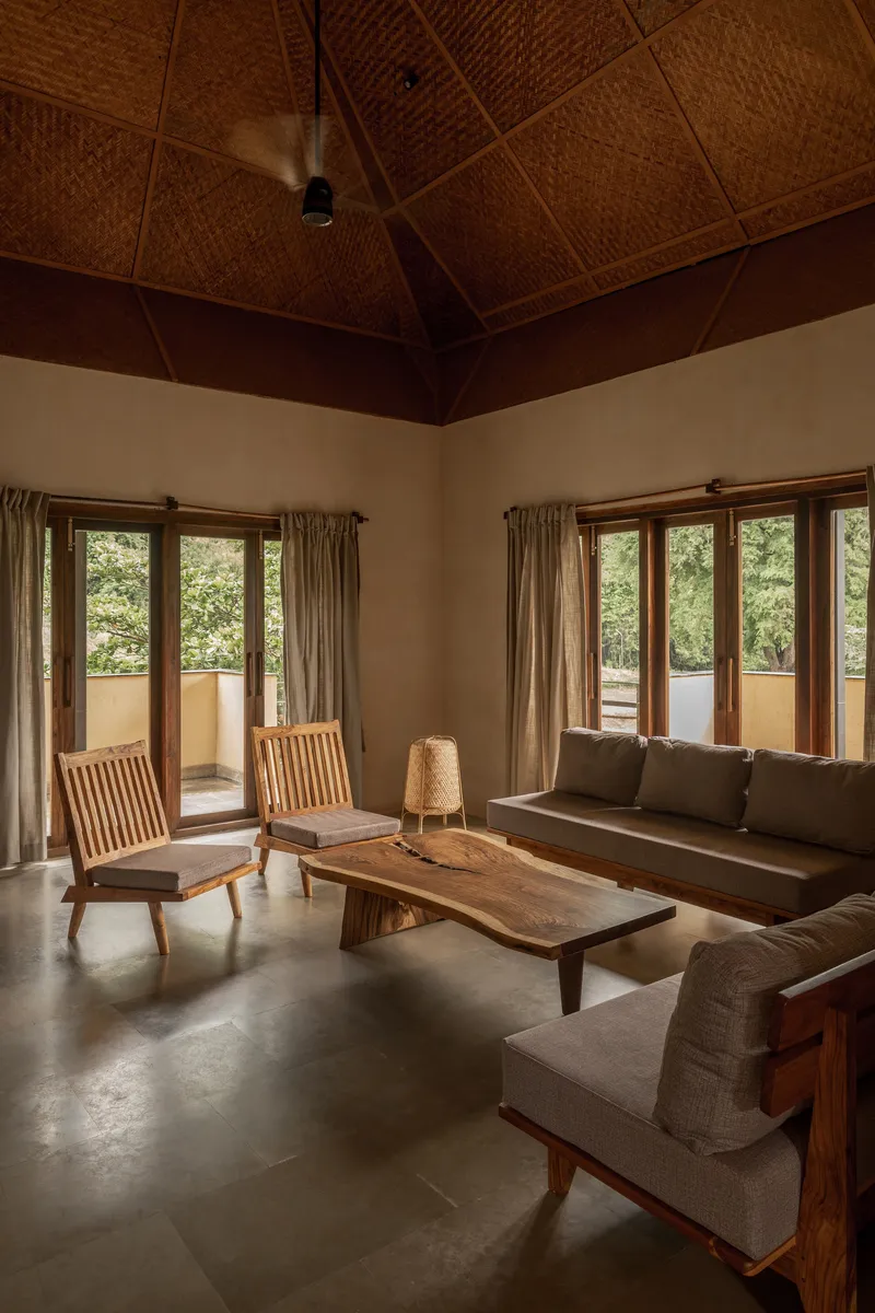 Living room with woven bamboo ceiling panels and timber doors opening to a terrace