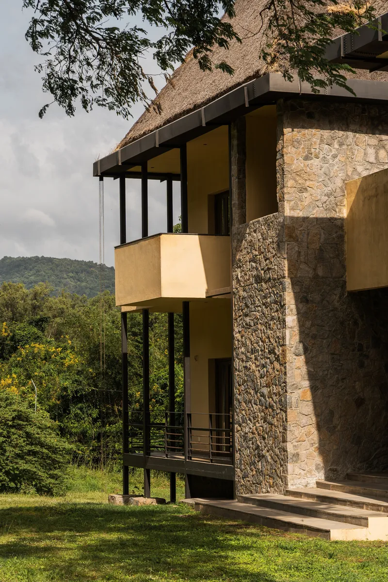 Detail of cantilevered yellow balcony boxes supported by black steel columns beside gabion stone walls