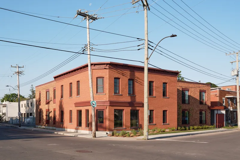 Corner view of the two-storey brick building with overhead power lines crossing the clear sky