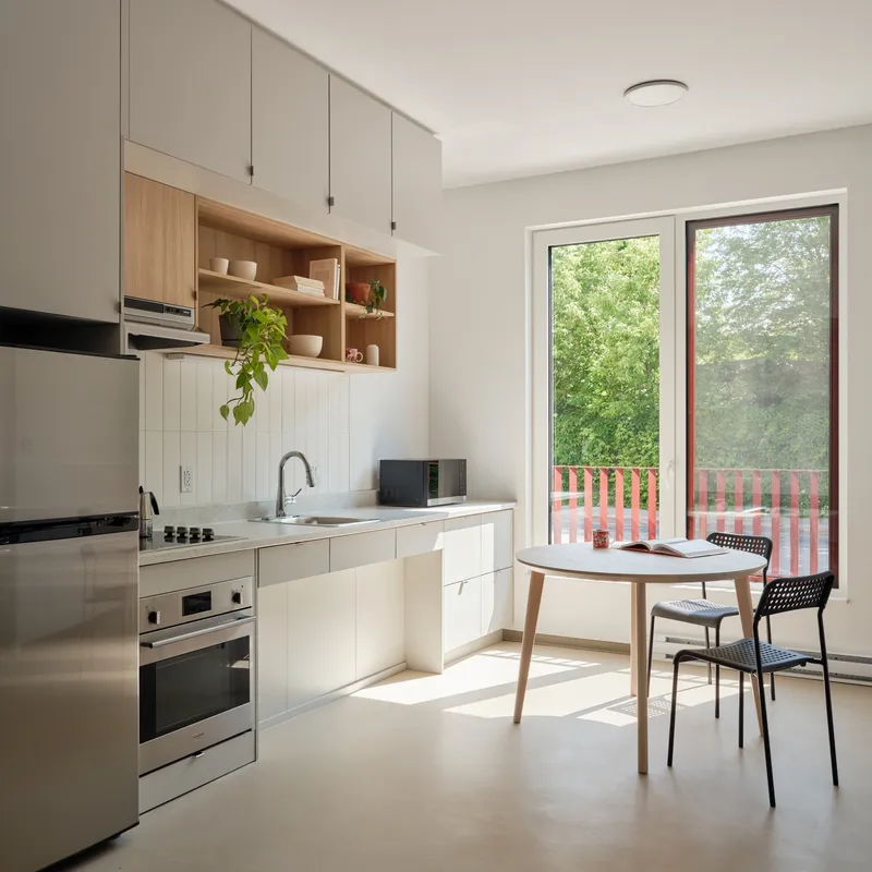 Compact kitchen with open shelving and glazed door overlooking a balcony with red metal railing