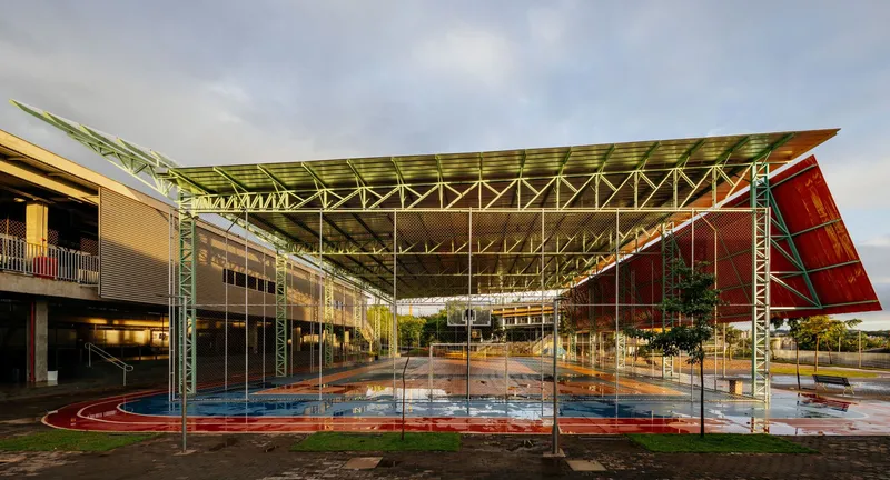 Underside of the exposed steel truss canopy spanning the courtyard with wet paving below