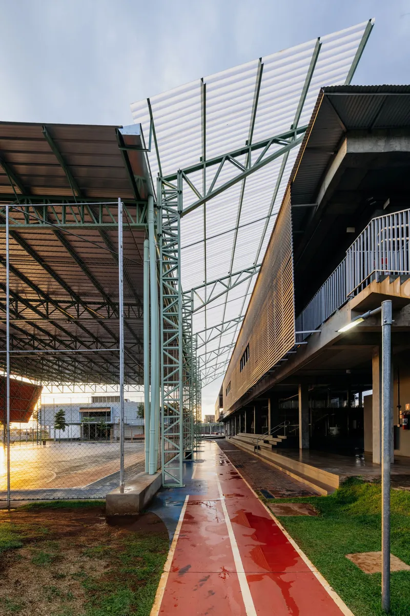 View along the covered walkway showing the angled white corrugated canopy supported by green steel trusses
